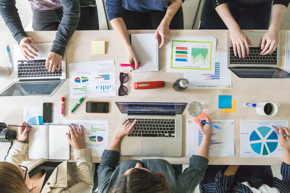 Team meeting for Private Label business strategy, with a group of professionals collaborating around a table with laptops, charts, and notes.